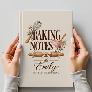 Peut inclure: Un journal à couverture rigide de couleur crème avec le texte BAKING NOTES, Emily et MY BAKING JOURNAL. Le design présente des illustrations d'un fouet, d'un bol mélangeur rose, d'un rouleau à pâtisserie en bois avec un nœud et des fleurs.
