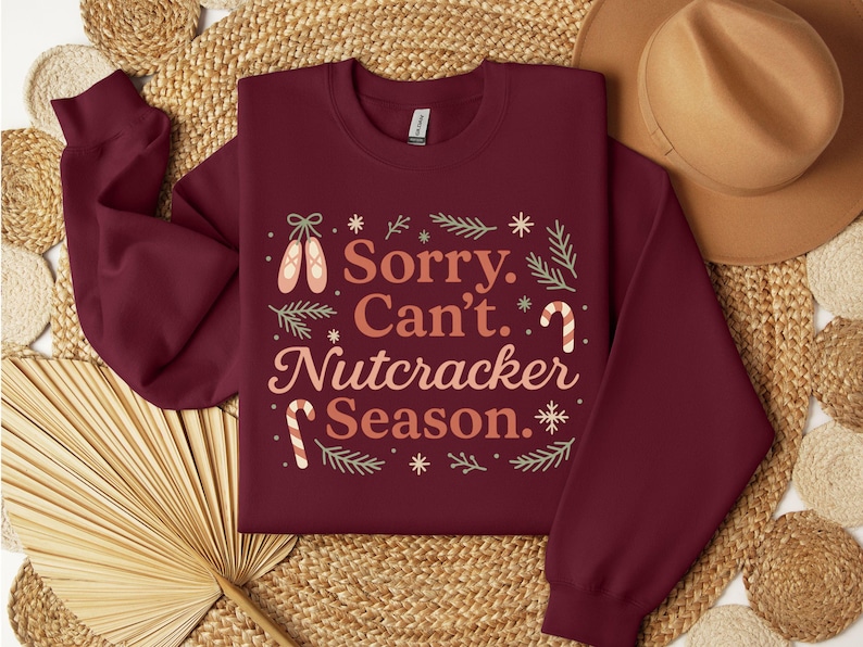 Pu&ograve; includere: Felpa bordeaux con la scritta "Sorry. Can't. Nutcracker Season." in un design festivo. Presenta scarpette da ballo, bastoncini di zucchero e fiocchi di neve. Un capo d'abbigliamento stagionale e accogliente.