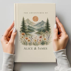May include: A cream-coloured journal with the text "THE ADVENTURES OF" at the top and "ALICE & JAMES" at the bottom. The cover features a watercolour landscape with mountains, a river, trees, flowers, and a sun.