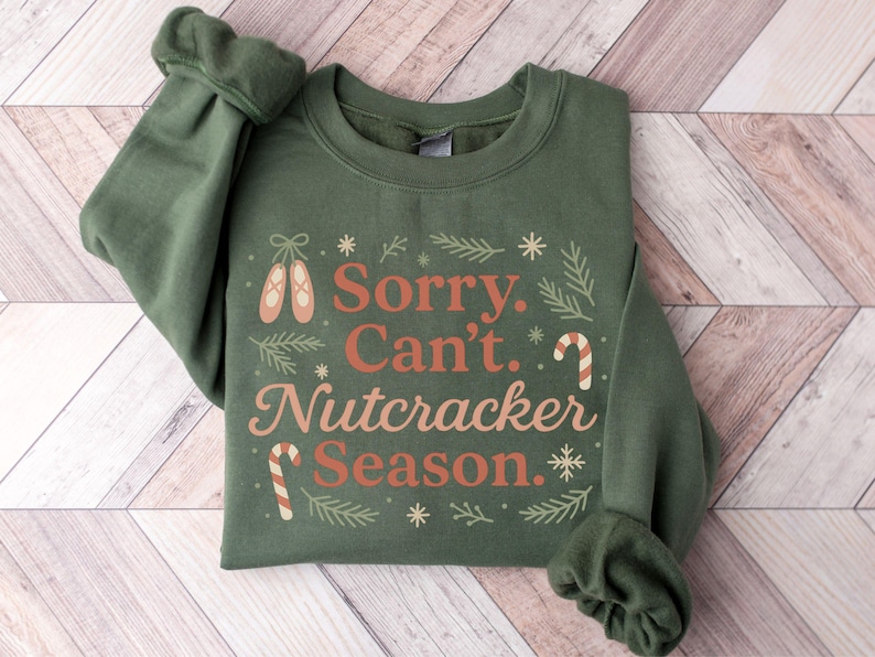 Pu&ograve; includere: Felpa verde con la scritta "Sorry. Can't. Nutcracker Season." in un design festivo. Il design include scarpette da ballo, bastoncini di zucchero e fiocchi di neve. Le maniche sono arricciate.