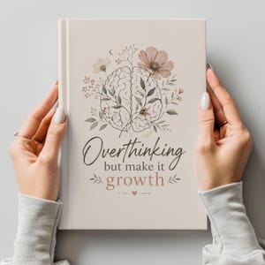 Puede incluir: Un diario crema con el texto "Overthinking but make it growth" en la portada. El diseño presenta una ilustración de un cerebro rodeado de flores y follaje en tonos suaves. El diario es sostenido por manos y tiene un diseño limpio y minimalista.