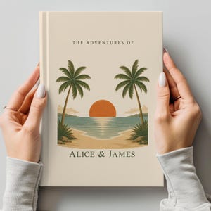 May include: A beige journal with a beach scene featuring palm trees, a setting sun, and the text "THE ADVENTURES OF" above "ALICE & JAMES". The journal is held by two hands.