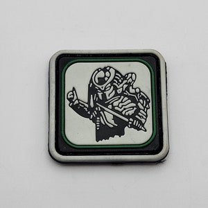 May include: A black and white patch with a green border. The patch features a stylized image of a creature with a raised fist.