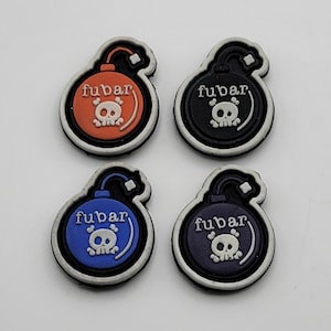 Peut inclure: Quatre patchs en forme de bombe de couleurs différentes avec un motif de crâne et d'os croisés et le mot "fubar" imprimé sur chacun.