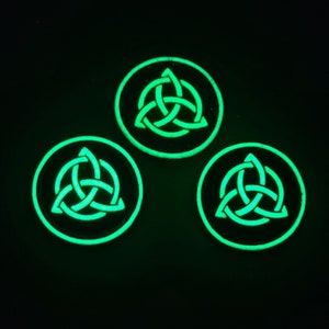 May include: Three round, black, glow-in-the-dark patches with a green Celtic knot design.
