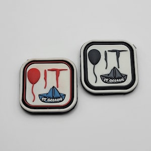 May include: Two white square patches with black borders. Each patch has a red or black balloon, a paper boat, and the text "IT" with a red or black axe. The text on the boat reads "SS Georgie".