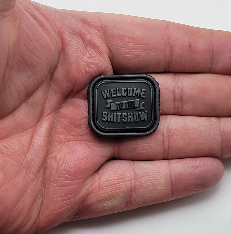 Pu&ograve; includere: Toppa quadrata nera con il testo "Welcome to the Shitshow" in lettere bianche.