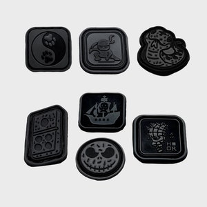 Pode incluir: Oito patches de borracha preta com diferentes designs. Os designs incluem um símbolo yin yang, um ninja, uma cobra, um navio pirata, um dominó, uma caveira e uma bomba.