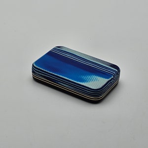 May include: A small, rectangular box with a blue and white striped pattern. The box has a black border and gold accents.