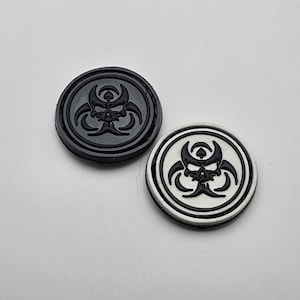 May include: Two round black and white biohazard symbol poker chips. The black chip has a white biohazard symbol and the white chip has a black biohazard symbol.
