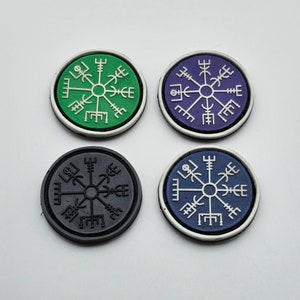 Peut inclure: Quatre patchs ronds et colorés avec un motif de boussole blanc. Les patchs sont vert, violet, noir et bleu.