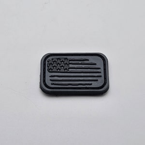 May include: A black rectangular patch with a raised, embossed American flag design.