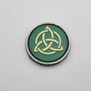 May include: A green and white circular patch with a white Celtic knot design.