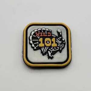 May include: A yellow, white, and black patch with a turkey illustration and the text "WILD 101".