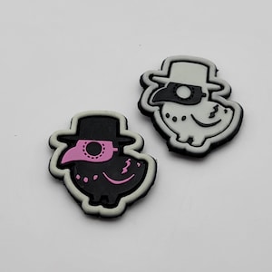 May include: Two black and white iron-on patches featuring a cartoon bird wearing a doctor's mask and hat. One patch has a pink mask and the other has a white mask.