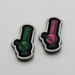 May include: Two iron-on patches featuring a green and a pink cartoon bong. The patches are white with black outlines.