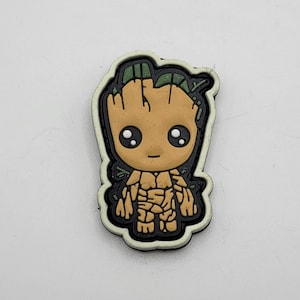 May include: A brown and green cartoon character with a large head and small body. The character has large eyes, a small mouth, and a tree-like design on its head. The character is surrounded by a black and white outline.