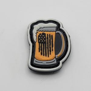 Könnte beinhalten: Ein schwarz-weißes amerikanisches Flaggen-Design auf einem gelben Bierkrug mit weißem Schaum oben. Der Krug ist schwarz-weiß umrandet und hat einen weißen Henkel.