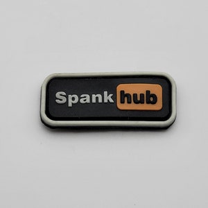 May include: Black and white rectangular patch with a white border. The patch has the text "Spankhub" in white letters with a smaller orange rectangle containing the word "hub" in white letters.