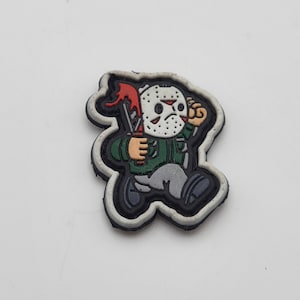 May include: A white, gray, and red rubber patch with a cartoon character wearing a hockey mask and holding a knife. The character is running and has a green shirt on.