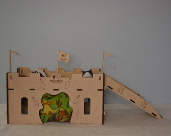May include: A wooden castle playhouse for small pets, featuring a ramp, a green and brown fabric bed, and a sign that reads "Paw-sitive Vibes Only".