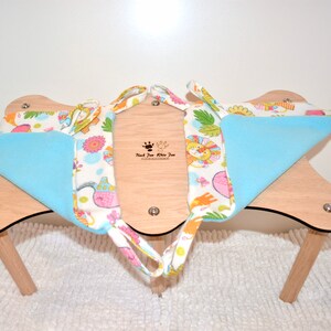 May include: A light blue and white fabric cat hammock with a colorful animal print. The hammock is attached to a wooden stand with four legs.