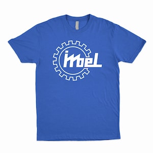 May include: Royal blue t-shirt with a white graphic. The graphic features a gear-shaped outline with the word "Imbel" in a stylized font. The shirt has a crew neck and short sleeves.