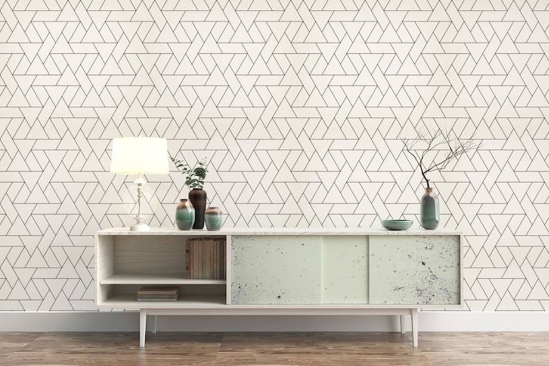 May include: A white cabinet with two doors and three shelves. The cabinet has a light wood finish and is decorated with a geometric pattern. The cabinet is sitting on a wooden floor. There is a lamp, a vase with branches, and two other vases on top of the cabinet.