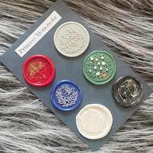 May include: A set of seven wax seals with different designs, including a tree, a wolf, a deer, a bird, and a flower. The seals are on a gray background with the text "Princess Mononoke" in white.