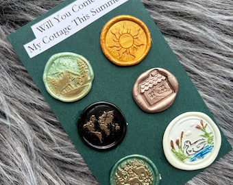 May include: A dark green card with six wax seals of various colors and designs. The seals include a sun, a house, a world map, a landscape, a deer, and a duck. Text on the card reads, "Will You Come to My Cottage This Summer?"