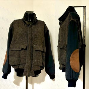 May include: A brown and black tweed bomber jacket with a zipper closure. The jacket has a black collar and cuffs, and brown leather elbow patches.