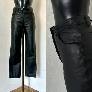 Puede incluir: Pantalón de cuero negro de pierna recta. El pantalón tiene una cremallera y trabillas para el cinturón.