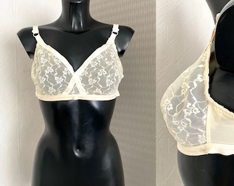 May include: A white lace bra with a delicate floral pattern. The bra has a V-neckline and adjustable straps.