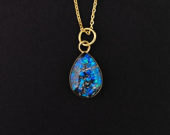 May include: A gold chain necklace with a teardrop-shaped pendant featuring a blue and black iridescent opal.