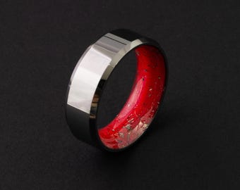 Peut inclure: Une bague en carbure de tungstène noire avec une incrustation rouge et dorée. La bague a un bord biseauté et une finition polie.