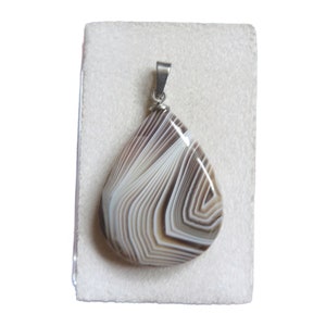 May include: A teardrop-shaped pendant made of white and brown agate with a silver bail.