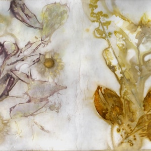 Könnte beinhalten: Ein rechteckiges Textilstück mit botanischen Öko-Drucken. Die linke Seite zeigt violette und gelbe Blumenabdrücke mit zarten Blütenblättern und Stängeln. Die rechte Seite zeigt goldbraune Blatt- und Pflanzensilhouetten auf weißem Grund.