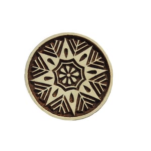 Könnte beinhalten: Ein runder Holzblock mit einem geschnitzten Design eines Sternbursts. Das Design ist in Braun und Weiß.