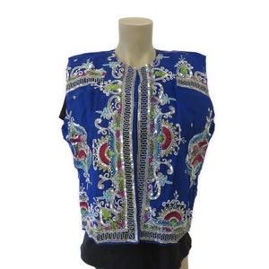 May include: A sleeveless blue vest with intricate silver and colorful embroidery. The vest has a high neckline and a button closure.
