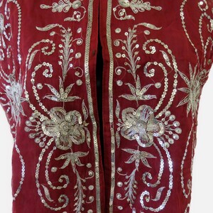 May include: A red sleeveless vest with silver sequins and embroidery in a floral pattern.