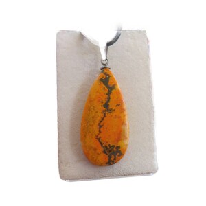Könnte beinhalten: Ein tropfenförmiger Anhänger aus orangefarbenem und schwarzem Jaspis mit einer silbernen Öse.