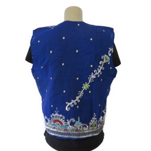 May include: A blue sleeveless vest with silver and colorful embroidery. The vest has a floral design and is decorated with small white dots.