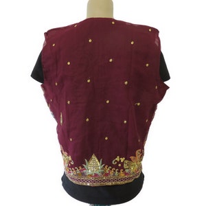 May include: A maroon sleeveless vest with gold embellishments and a floral design around the bottom.