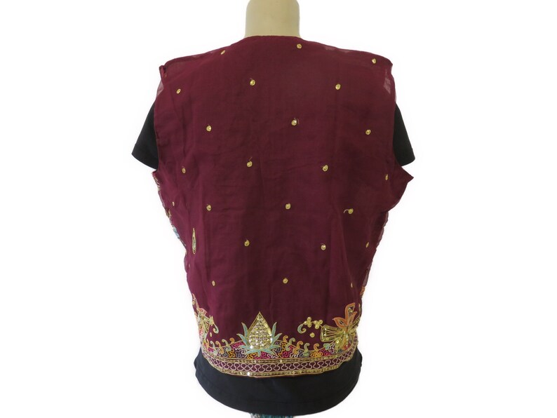 May include: A maroon sleeveless vest with gold embellishments and a floral design around the bottom.