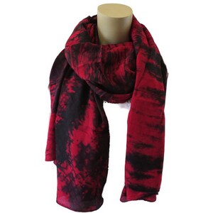 Könnte beinhalten: Ein rot-schwarzer Batik-Schal. Der Schal ist aus einem weichen, leichten Stoff gefertigt und perfekt, um jedem Outfit einen Hauch von Farbe zu verleihen.