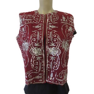 May include: A sleeveless vest with a burgundy base and silver embroidery. The embroidery features floral patterns and swirls.