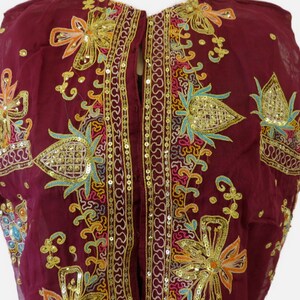 May include: A maroon sleeveless top with gold, turquoise, and pink embroidery and sequins. The top has a button closure down the front.