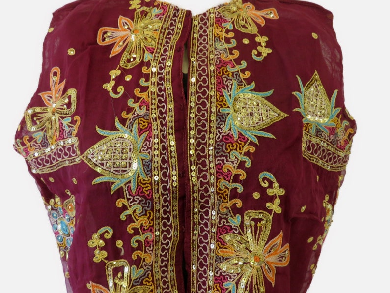 May include: A maroon sleeveless top with gold, turquoise, and pink embroidery and sequins. The top has a button closure down the front.