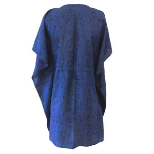 Può includere: Un caftano blu con motivo, scollo a V e maniche corte. Il tessuto ha una lucentezza sottile e una silhouette fluida.