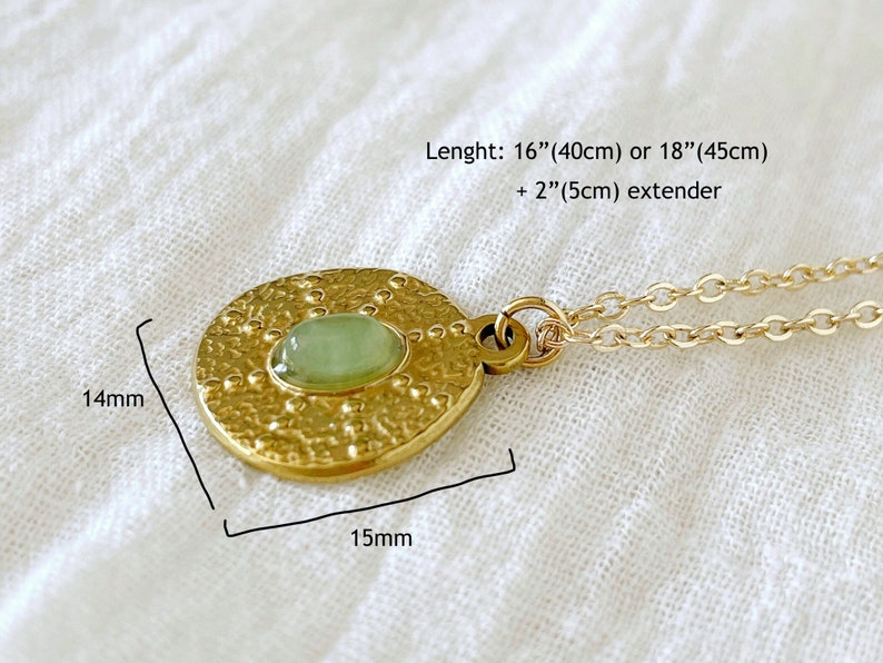 Gold necklace with a round pendant featuring a green gemstone. The pendant is 1.5 inches in diameter and has a textured surface. The necklace is 16 inches long with a 2-inch extender.